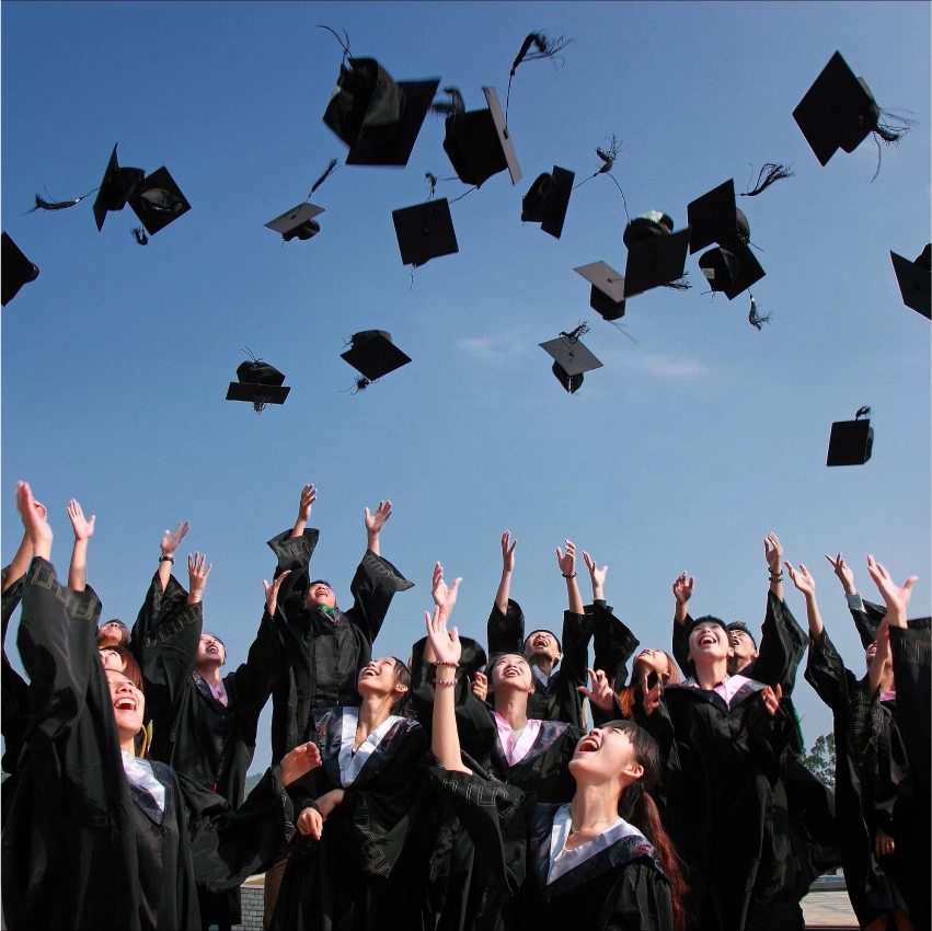 Graduates celebrating by throwing caps in air.