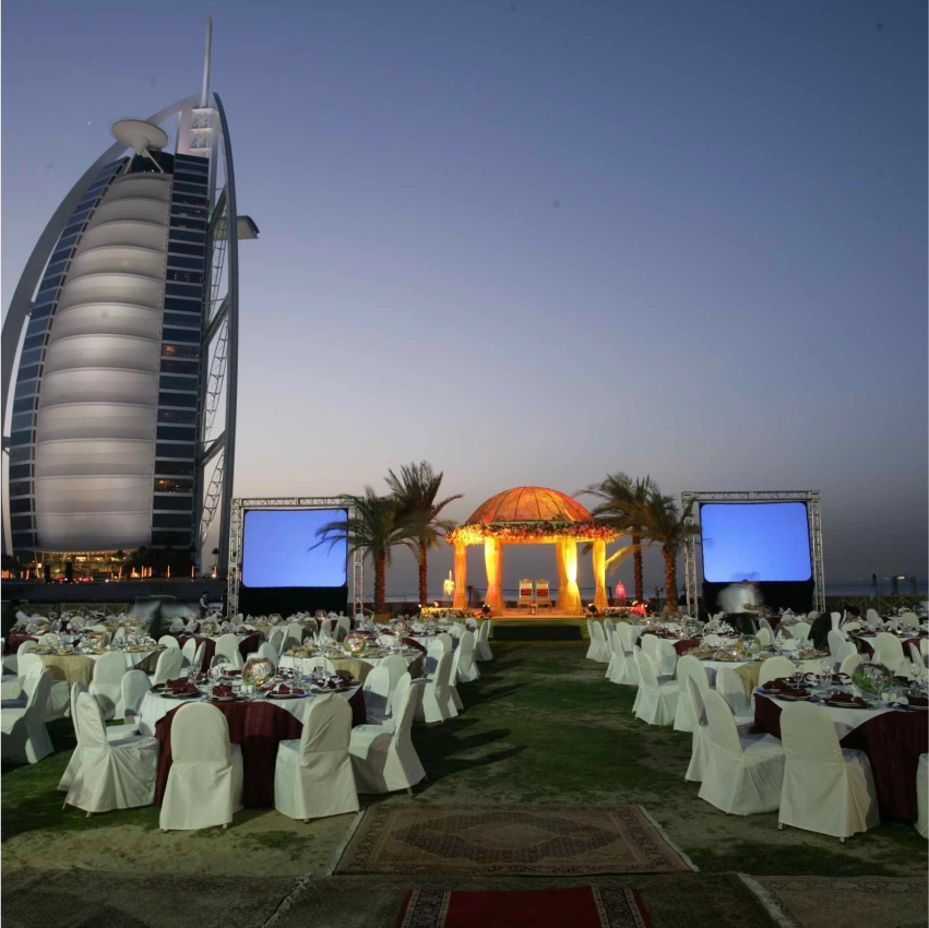 Outdoor event near iconic Dubai hotel at sunset.